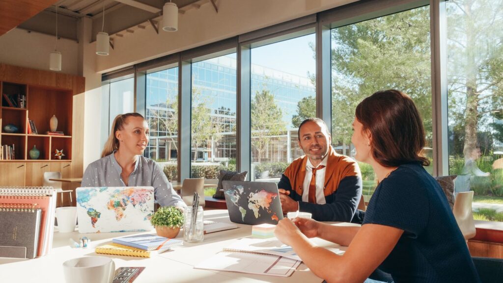Photo by Kindel Media Three diverse professionals collaborate in a bright, modern workspace.